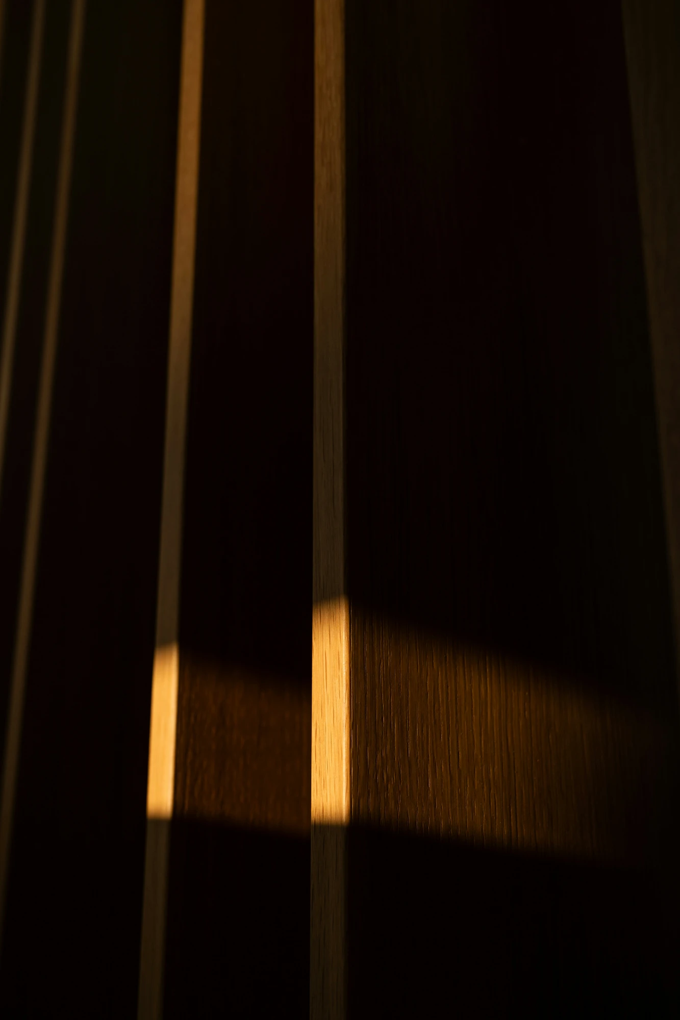 Vertical wooden slats lit by a horizontal band of warm sunlight